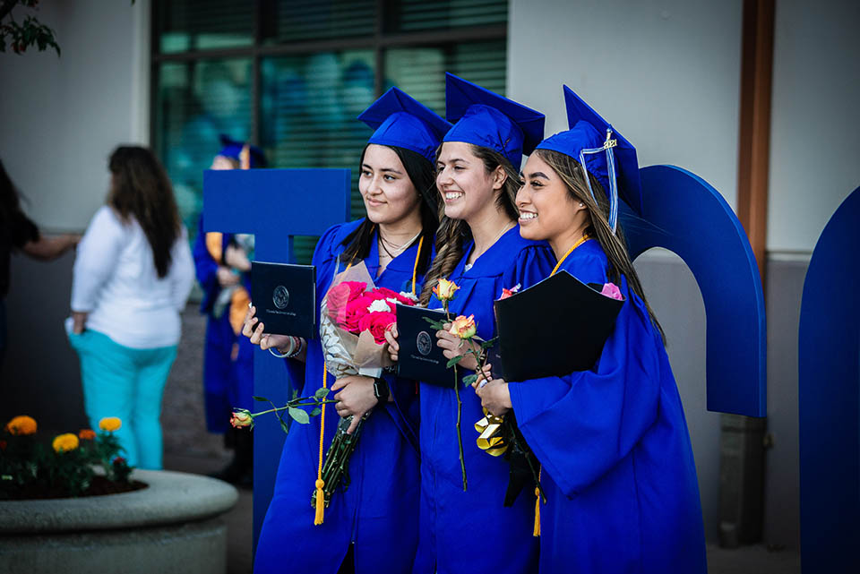 Three students at Graduation in their cap and gowns 2021