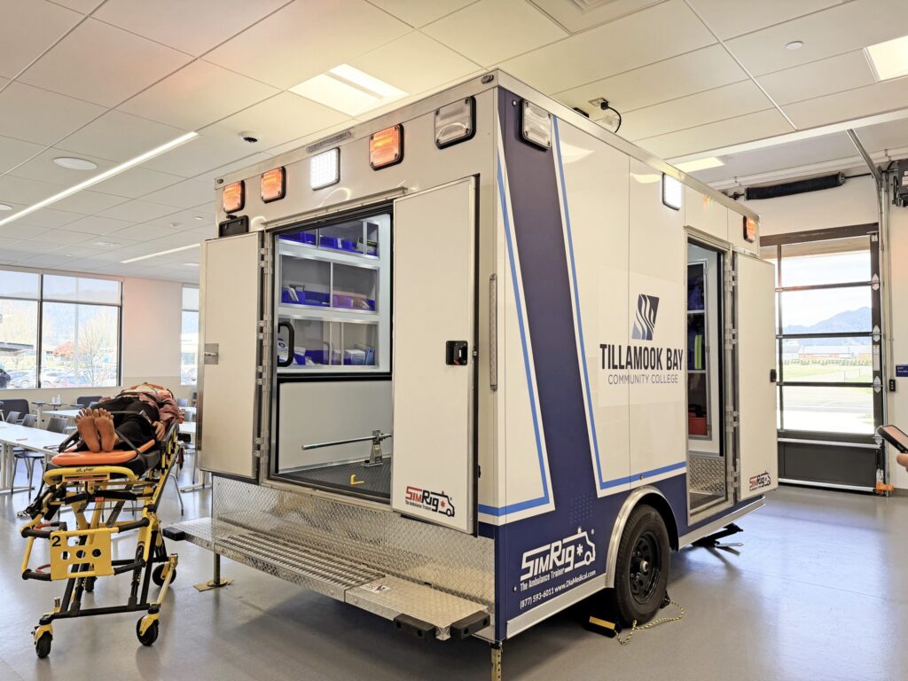 Ambulance simulator inside a medical-grade classroom. The stretcher is out and the lights on top are on.